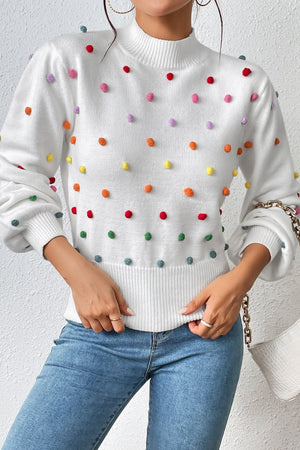 White knit sweater with colorful pom-pom embellishments and mock neck