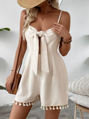 Beige textured romper with bow front, cutout, and tassel trim.