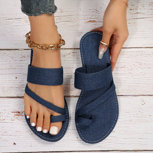 Dark blue denim crisscross toe loop sandals with white stitching.