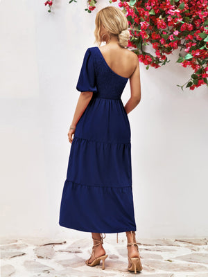 Dark blue smocked bodice tiered one-shoulder dress with puff sleeve and midi length.