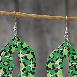 Green leopard print drop earrings with cutouts, hanging from a branch.