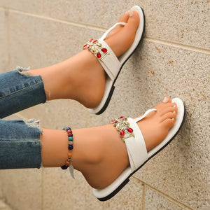 White jeweled toe-post flat sandals with red and clear gem embellishments.