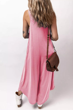 Pink wide leg jumpsuit with pockets and a crossbody bag.
