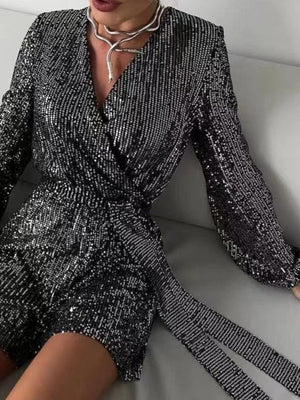 Black sequin wrap romper with blouson sleeves and tie waist.