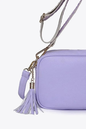 Textured lavender crossbody bag with tassel detail and adjustable strap.