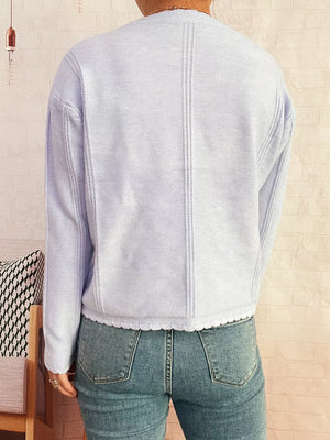 Light blue knit cardigan with scalloped hem and vertical seam details