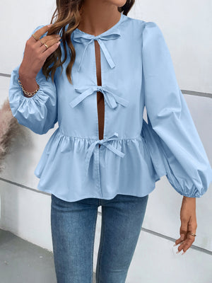 Light blue peplum blouse with keyhole neckline and bow details, long puff sleeves.
