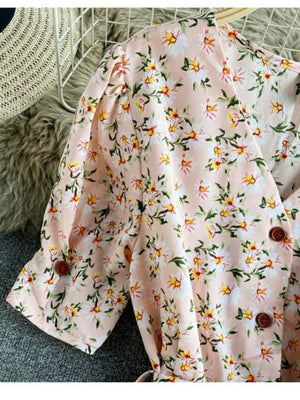 Pink floral v-neck midi dress with short puff sleeves and button details.