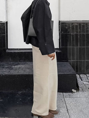 Chic cotton midi skirt with slit in beige, styled with a black jacket and bag.