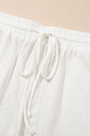 White textured knit drawstring shorts with a detailed pattern and tie waist.