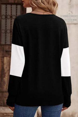 Black knit sweater with white colorblock sleeves and button cuffs.