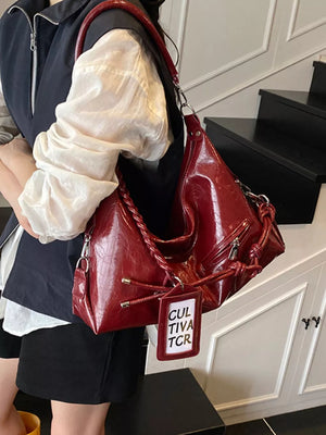 Red braided strap shoulder bag with embossed texture and zipper details.
