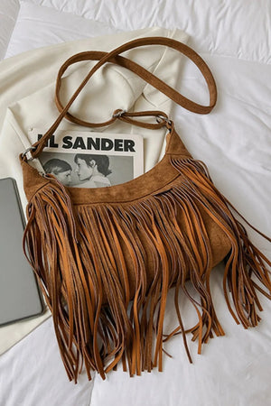 Brown suede crescent crossbody bag with long fringe detail and adjustable strap.