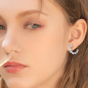 Silver Celestial Arc Moissanite Earrings with sparkling stones on a woman's ear.