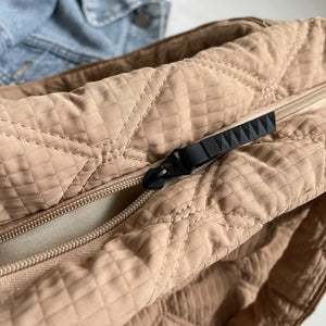 Quilted tote bag in camel with a textured diamond pattern and black zipper pull.