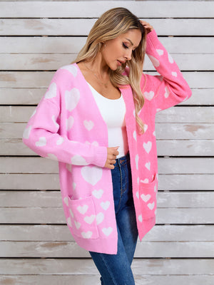 Pink split-panel cardigan with white hearts, open front, long sleeves, and pockets.