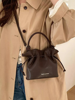 Brown pu leather cinch-top crossbody bag with drawstring closure and top handle.