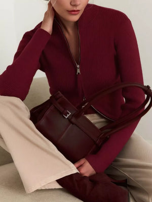 Burgundy ribbed zip-up cardigan with mock neck, styled with cream pants and a matching handbag.