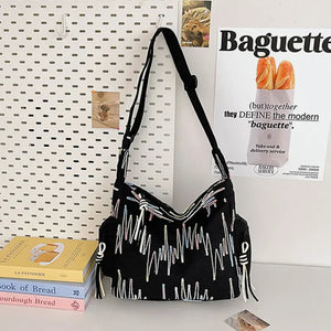 Black slouchy shoulder bag with embroidered abstract pattern and tassel details