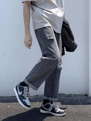Distressed relaxed fit men's jeans in dark gray with cuffed hems.