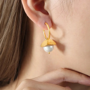 Gold hoop earrings with a petal-shaped accent and a pearl drop.