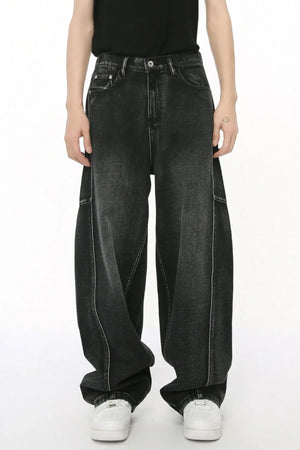 Dark wash denim trousers with exaggerated seam details and a wide leg