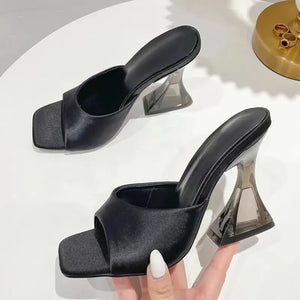 Black satin mules with a square toe and sculpted clear heel.
