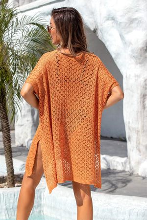 Open-knit orange beach poncho with short sleeves and side slits, styled casually.