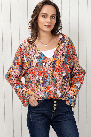 Painterly floral oversized blouse with V-neck and flared sleeves, worn with a white tank and jeans.