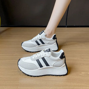 White platform trainers with black stripes and a chunky sole.