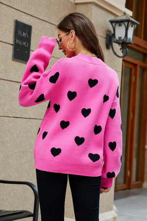 Pink knit sweater with black heart pattern and balloon sleeves.
