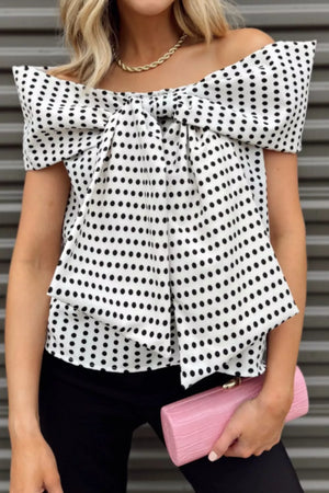 Chic off-shoulder polka dot blouse with a large bow detail and short sleeves.