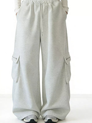 Gray cotton wide-leg cargo sweatpants with drawstring waist and zippered pockets.
