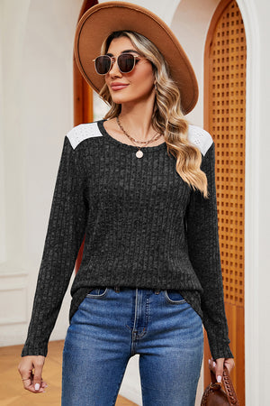 Black ribbed knit top with eyelet shoulder detail and crew neck.