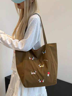 Brown shoulder bag with embroidered dachshunds and a mushroom detail.