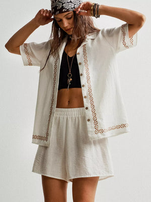 White linen two-piece set with geometric embroidery, button-up shirt and elastic waist shorts.