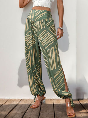 Moss green palazzo trousers with abstract print, smocked waist, and ankle ties.