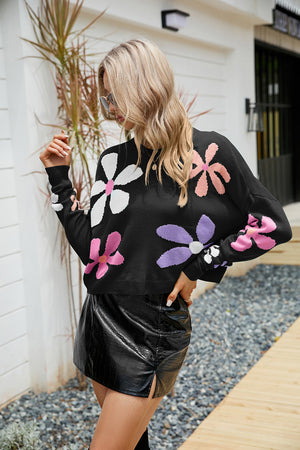 Black acrylic sweater with multicolor daisy motif and drop shoulders.