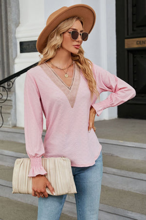 Blush pink textured blouse with lace V-neck and smocked cuffs.