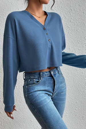 Dusty blue waffle knit crop top with henley neckline and long sleeves.