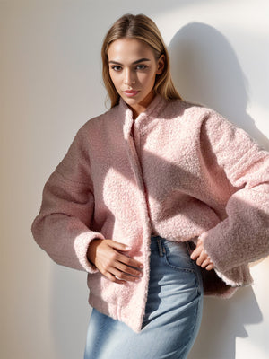 Textured blush pink bouclé bomber jacket with rounded neck and snap closure.