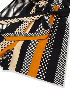 Black belted romper with polka dot and stripe patterns and a sash tie detail.