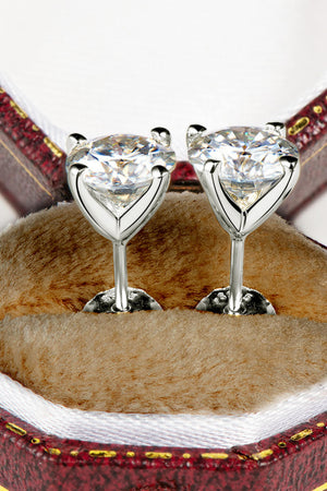 Silver moissanite solitaire stud earrings with sculpted settings in a jewelry box.
