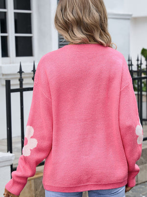 Blush pink acrylic intarsia knit cardigan with white floral details on sleeves.
