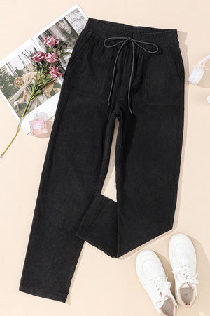 Black corduroy drawstring trousers with slant pockets and a relaxed fit.