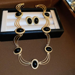 Gold oval stone stud earrings with black gemstones and matching necklace.