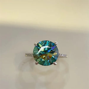 Radiant teal moissanite pavé ring in silver with a large round-cut center stone.