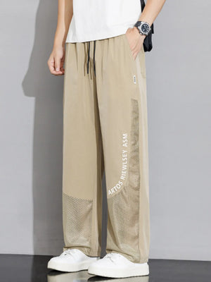 Khaki sweatpants with wide legs, mesh panels, and graphic text detail.