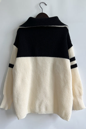 Ribbed knit quarter-zip sweater in cream and black with stripe detail on sleeves.