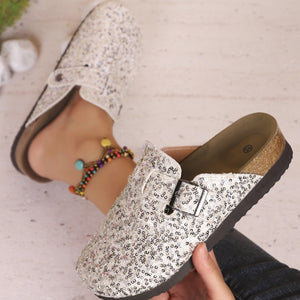 Sparkling sequin slip-on mules in white with decorative buckle detail.